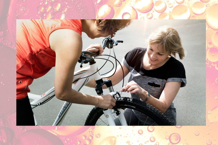 Two women working on a bike to adjust the brakes