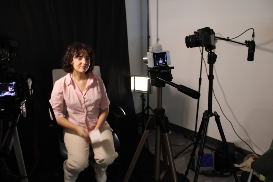 girl poses in front of green screen and cameras