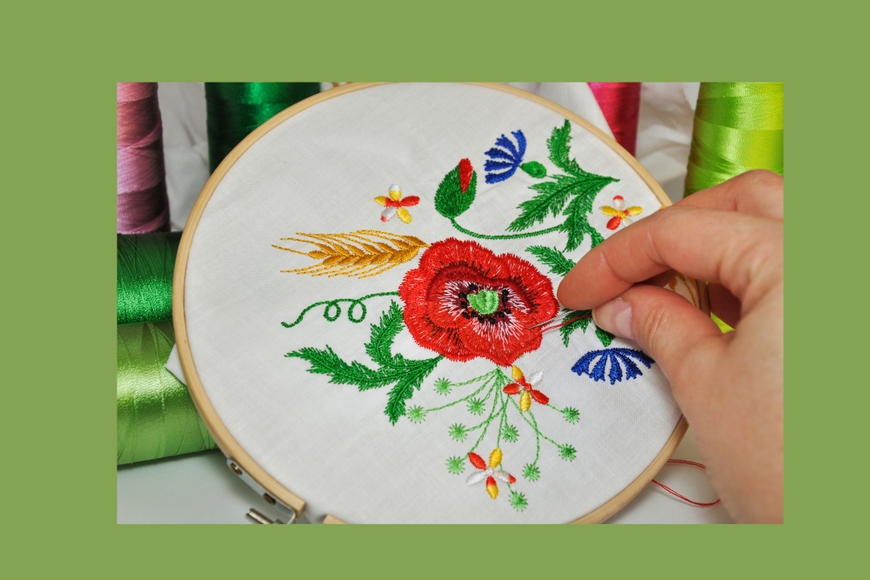 embroidery hoop with  vivid flowers and a hand with embroidery needle