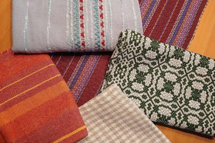 Colorful woven fabrics with stripes, plaid, and circular patterns in colors of orange, red, purple, grey, green, and beige.