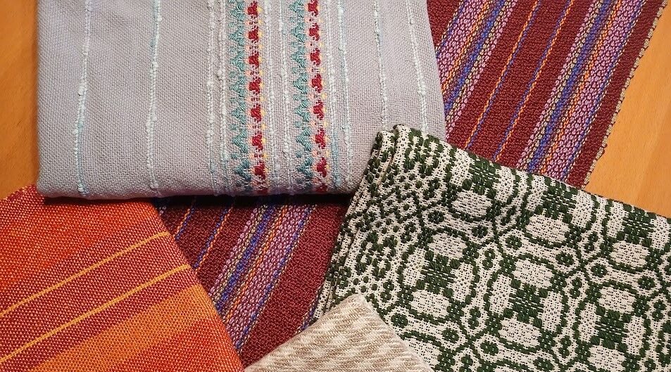 Colorful woven fabrics with stripes, squares, and circular patterns in greys, reds, greens, oranges, and reds.