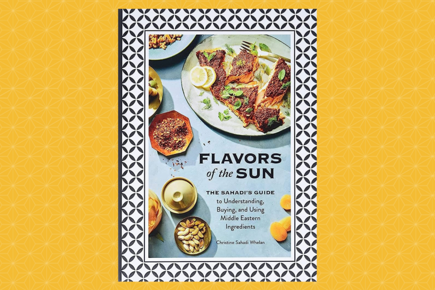 Book cover has a geometric frame and shows a large white plate serving spiced, seared fish garnished with lemon slices and green herb leaves (mint or oregano?) with smaller dishes of a spice blend, shelled nuts, and other small offerings.