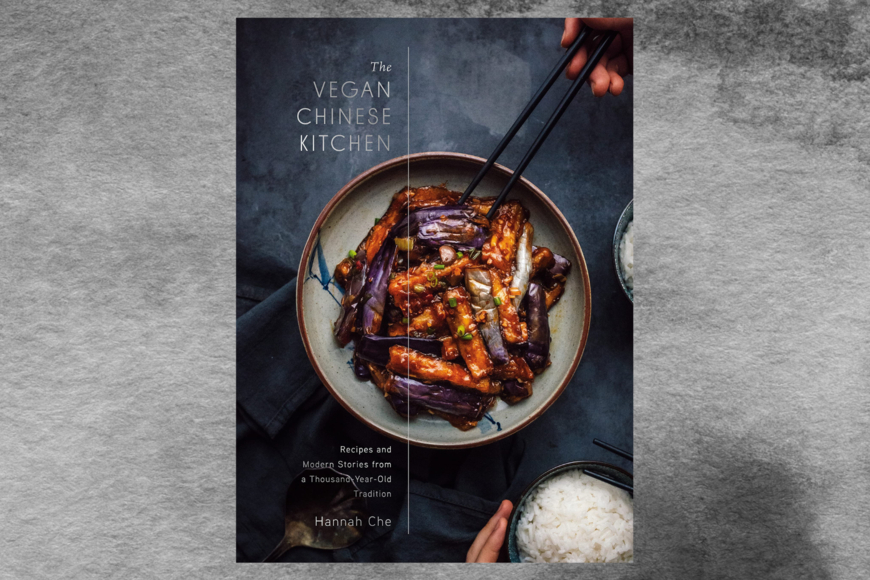 Center of book cover is a tantalizing dish of sauteed eggplant. A hand is about to pick up a piece of eggplant with a pair of chopsticks. A bowl of mounded white rice is in the lower right corner, all on a variegated blue-gray background.ook cover shows a face made of vegetables: broccoli floret hair, rosemary sprig eyebrows, ginger slice eyes, mushroom slice nose, and a yellow crookneck squash mouth, upturned in a smile.