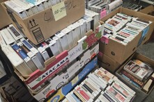 Many cardboard boxes filled with used books on CD. 