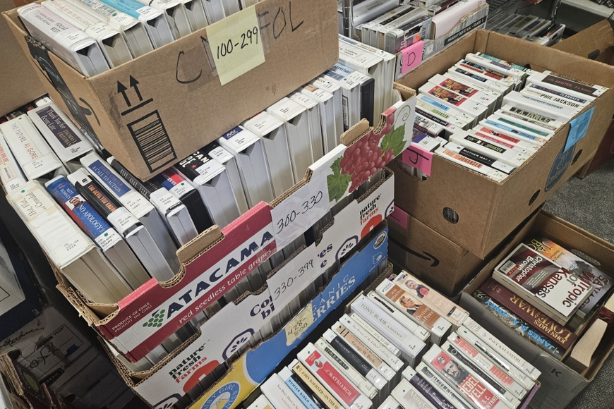 Many cardboard boxes filled with used books on CD.