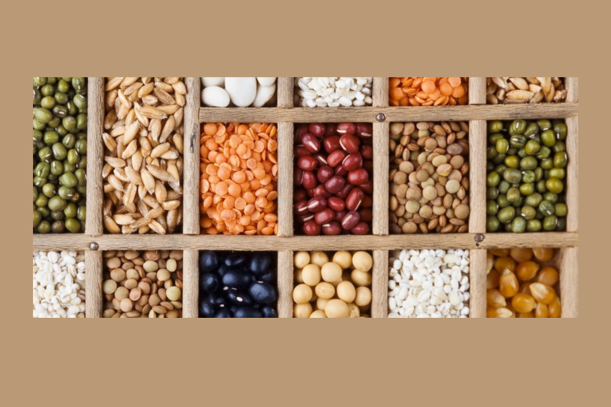 An image of various seeds in a wooden sectional box. 