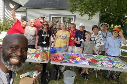 People standing around a table painting on a large canvas