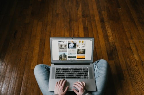Man sitting on wood floor using laptop