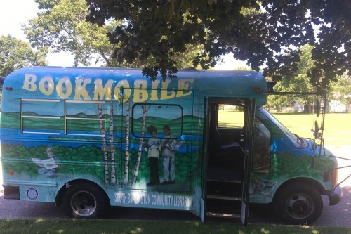 Bookmobile parked on street with trees above