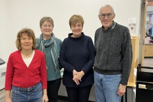 Four people wearing sweaters standing in a room