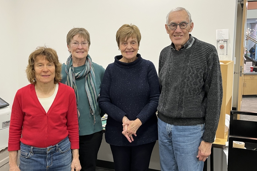 Four people wearing sweaters standing in a room